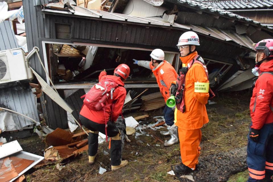 Firefighters search a collapsed house for survivors (JIJI Press/AFP via Getty)