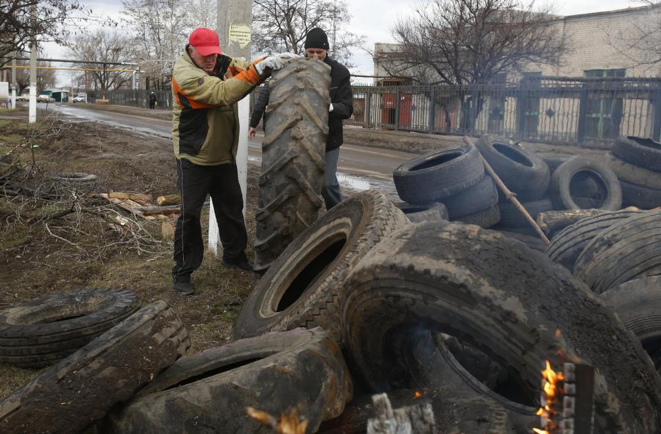 Pro Russian activists block a road with car tires near the armory Ukrainian army to prevent the export of arms and ammunition in the village of Poraskoveyevka, eastern Ukraine, Thursday, March 20, 2014. The disheveled men barricading the muddy lane leading into a military base in this eastern Ukraine village say they're taking a stand to defend Russian-speakers. (AP Photo/Sergei Grits)