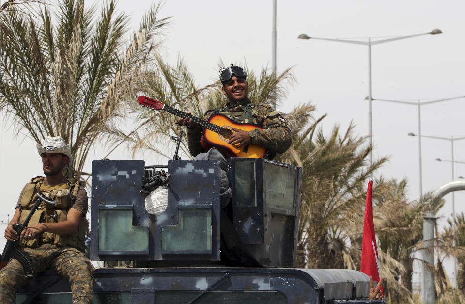 In this Friday, April 3, 2015 file photo, an Iraqi soldier plays his guitar atop his armored vehicle on the main road between Baghdad and Tikrit, 80 miles north of Baghdad, Iraq. (AP Photo/Khalid Mohammed, File)