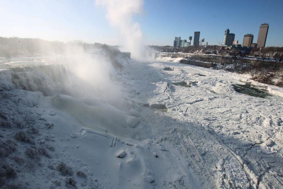 The area surrounding Niagara Falls, N.Y., is coated in a layer of ice in Niagara Falls State Park on Thursday, Jan. 9, 2014. Niagara Falls hasn't frozen over, but it has become an icy spectacle, thanks to a blast of arctic wind and cold that blew around and froze the mist on surfaces and landscaping. Despite the urban legends, Niagara Falls doesn't freeze solid in the winter, tourism officials say. A section of the American Falls, one of three waterfalls that make up the natural attraction, has frozen. The Niagara River rapids and larger Horseshoe Falls continue to flow unimpeded. (AP Photo/The Buffalo News, Sharon Cantillon) MANDATORY CREDIT