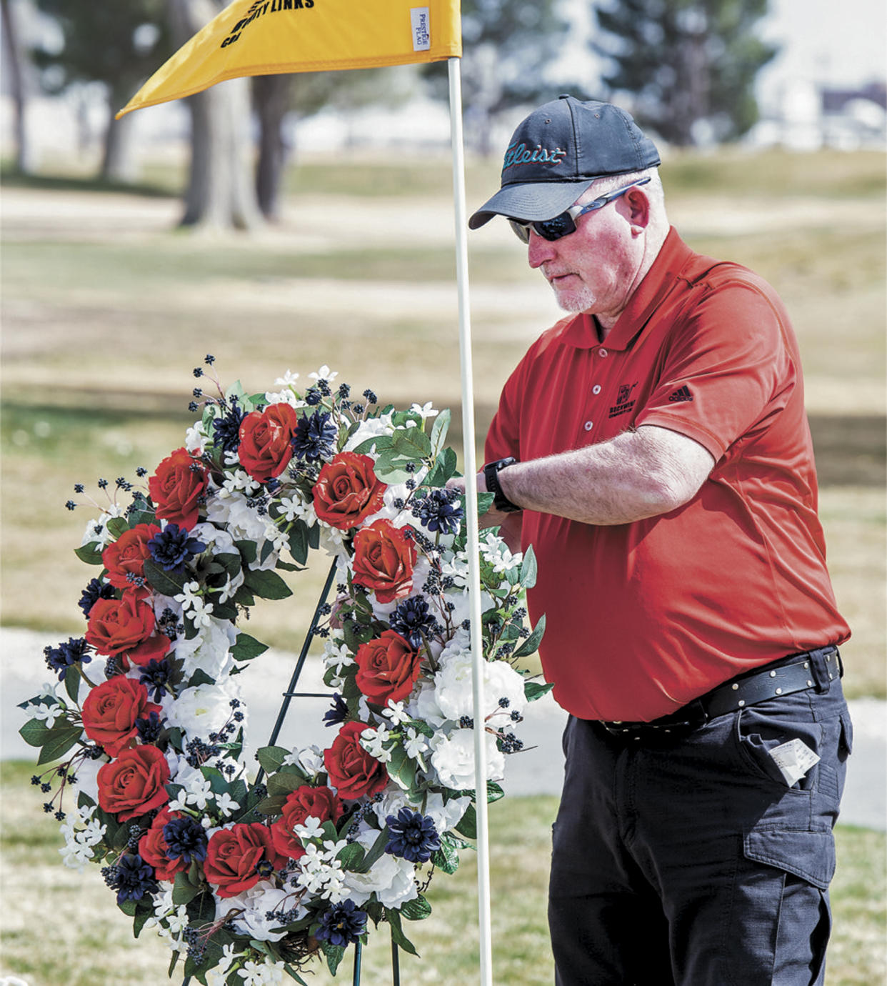 Doug McDaniel, recreation director at Rockwinds Community Links in Hobbs, New Mexico, sets a wreath at a memorial to the six golfers and their coach who were killed in an accident, Wednesday, March 16, 2022. McDaniel said Rockwinds staff were out early Wednesday setting up the memorial to the team, which plays and practices at the course. Nine people have died in a fiery, head-on collision in West Texas, including six students and a coach from a New Mexico university who were returning home from a golf tournament, authorities said. (Andy Brosig/Hobbs News-Sun via AP)