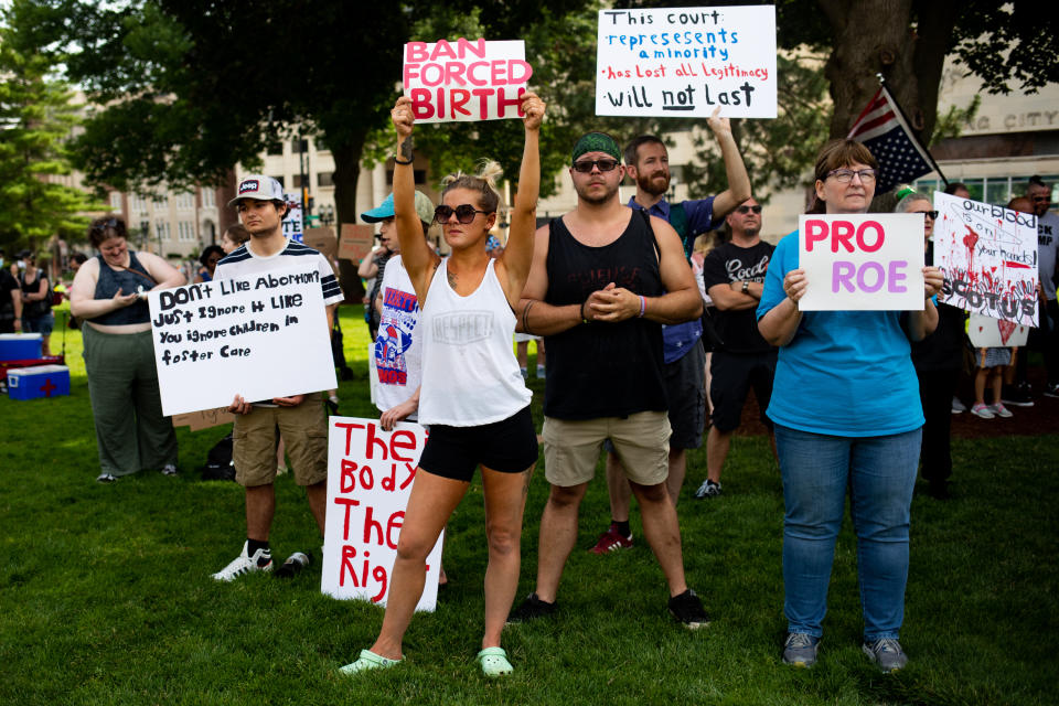 Abortion rights demonstrators hold signs reading: Don't like abortion? Just ignore it like you ignore children in foster care. Ban forced birth. And others.