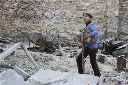 REFILE - CORRECTING TYPO A boy collects his belongings after what activists said where explosive barrels thrown by forces loyal to Syria's President Bashar al-Assad that killed at least 11 people in Masaken Hanano in Aleppo February 8, 2014. REUTERS/Hosam Katan