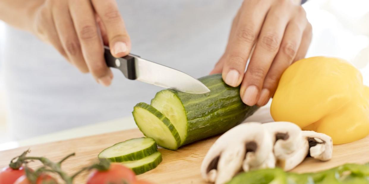 woman chopping fresh cucumber