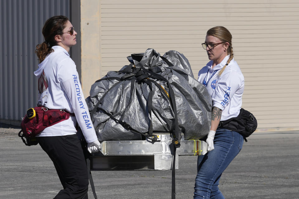 Recovery team members carry a capsule containing NASA's first asteroid samples to a temporary clean room at Dugway Proving Ground in Utah on Sunday, Sept. 24, 2023. The Osiris-Rex spacecraft released the capsule following a seven-year journey to asteroid Bennu and back. (AP Photo/Rick Bowmer, Pool)