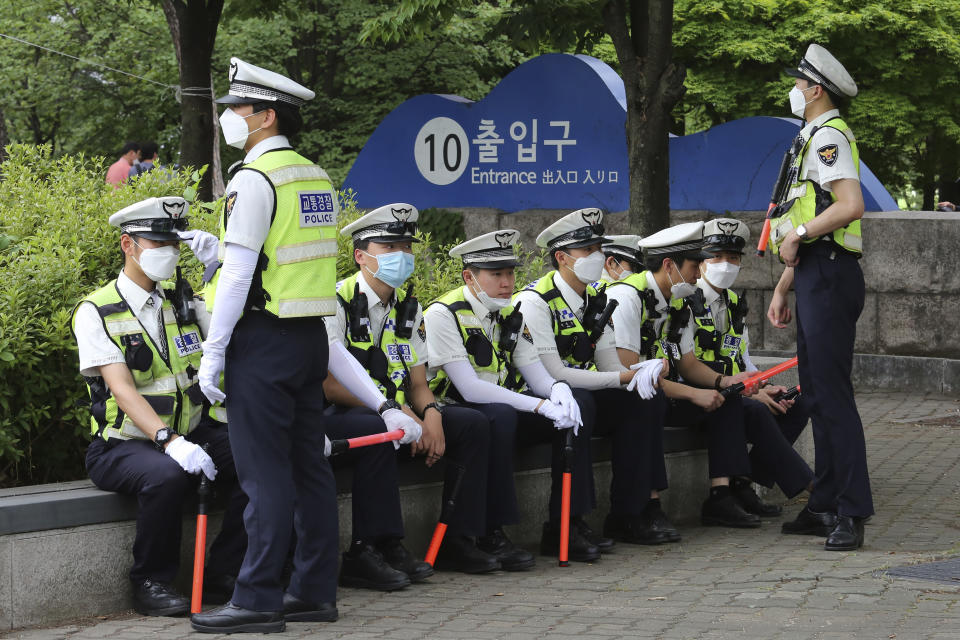 Traffic police officers wearing face masks to help protect against the spread of the new coronavirus take a rest while workers stage a rally against the government's labor policy in Seoul, South Korea, Wednesday, June 10, 2020. (AP Photo/Ahn Young-joon)