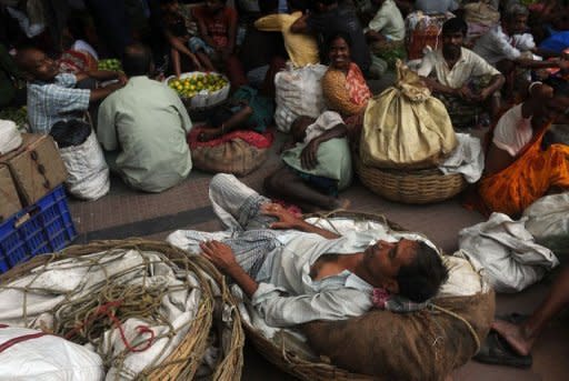 Indian passengers and vendors wait on the platform of Sealdah train station for the resumption of services during a power failure in Kolkata