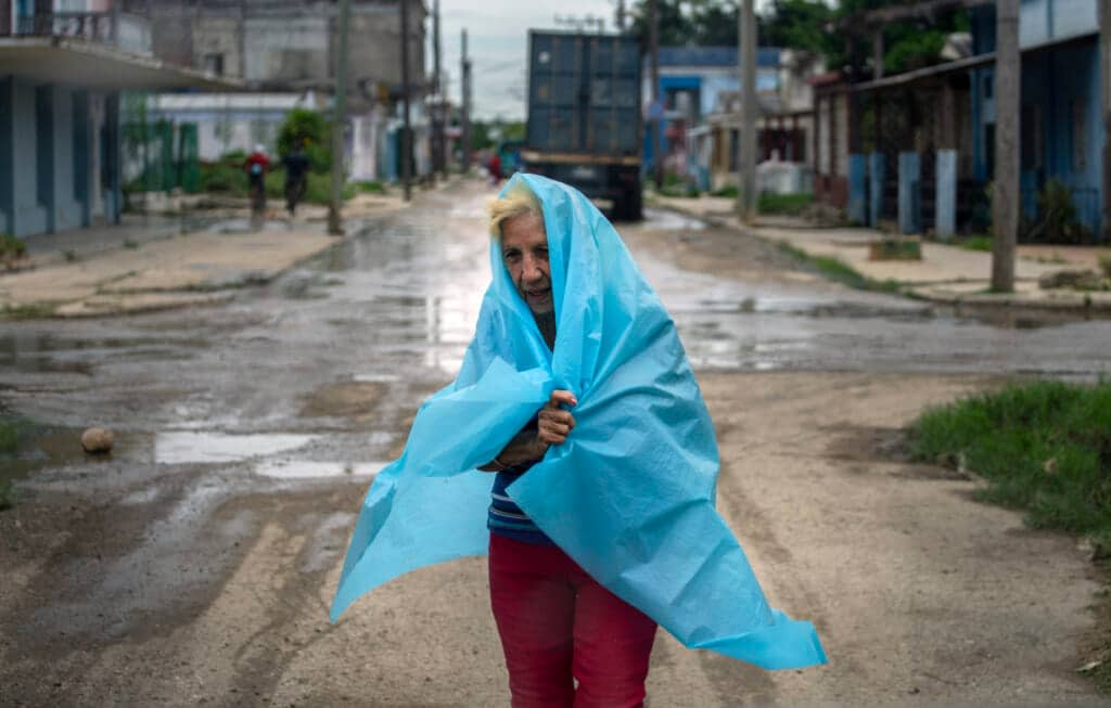 A resident uses plastic as protection from the rain in Batabano, Cuba, Monday, Sept. 26, 2022. Hurricane Ian is quickly gaining monstrous strength as it moves over oceans partly heated up by climate change. (AP Photo/Ramon Espinosa, File)