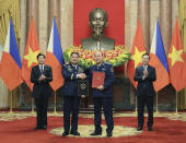 Philippine President Ferdinand Marcos Jr., left, and Vietnamese President Vo Van Thuong, right, look on as the Philippine Coastguard Commander Adm. Ronnie Gil Gavan and Vietnamese Coastguard Commander Le Quang Dao exchange signed documents in Hanoi, Vietnam Tuesday, Jan. 30, 2024. Marcos is on a visit to Hanoi to boost the bilateral relation with the fellow Southeast Asian nation. (Hoang Thong Nhat/VNA via AP)