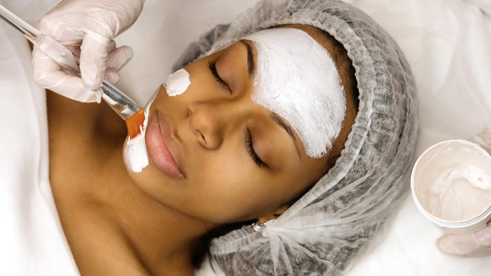 Application of a cosmetology mask on the face of a young afro american woman.