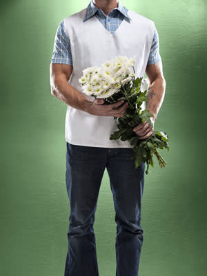 Man holding flowers towards someone.