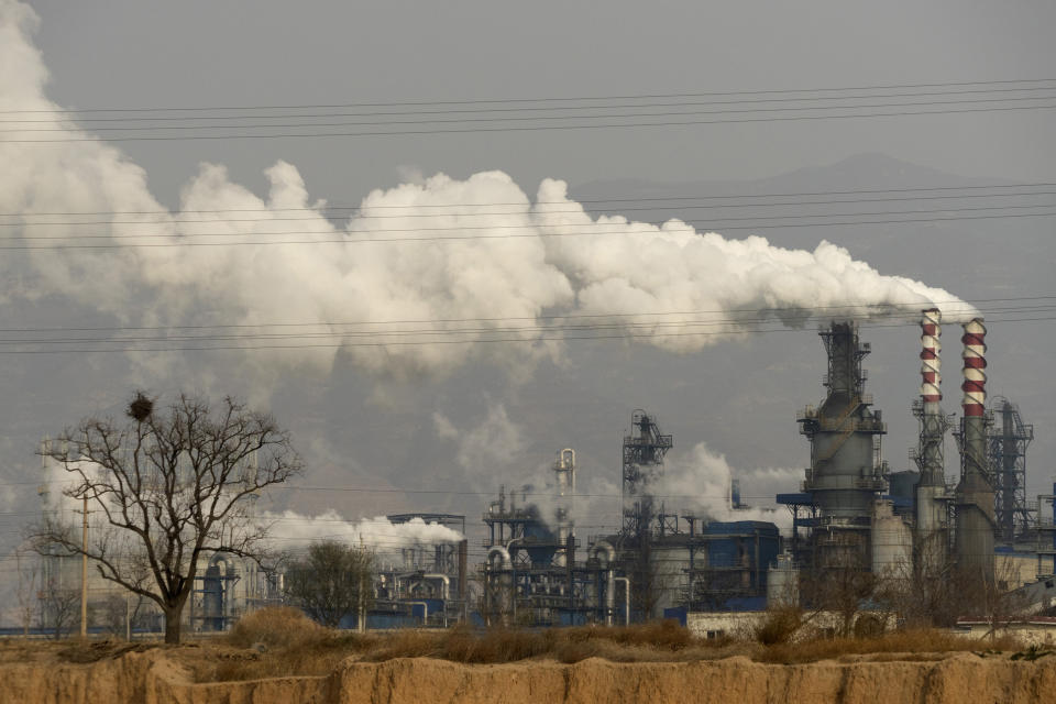 In this Nov. 28, 2019, photo, smoke and steam rise from a coal processing plant that produces carbon black, an ingredient in steel manufacturing, in Hejin in central China's Shanxi Province. As world leaders gather in Madrid to discuss how to slow the warming of the planet, a spotlight is falling on China, the top emitter of greenhouse gases. China burns about half the coal used globally each year. Yet it's also the leading market for solar panels, wind turbines and electric vehicles. (AP Photo/Olivia Zhang)