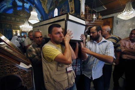 People carry a casket holding the body of Palestinian Christian woman Jalila Faraj Ayyad, whom medics said was killed in an Israeli air strike, during her funeral at the Saint Porfirios church in Gaza City July 27, 2014. REUTERS/Suhaib Salem