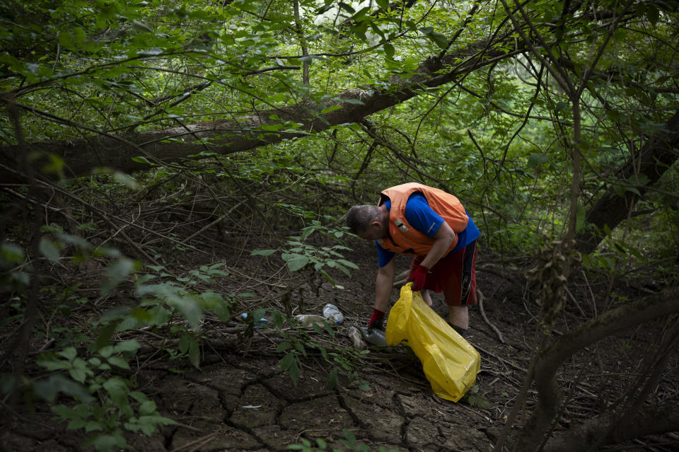 A volunteer collects rubbish from the banks of Tisza River near Tiszaroff, Hungary, Tuesday, Aug. 1, 2023. Since its start in 2013, participants in the annual Plastic Cup competition — which offers a prize for those who collect the most trash each year — have gathered more than 330 tons (around 727,000 pounds) of waste from the Tisza and other Hungarian waters. (AP Photo/Denes Erdos)