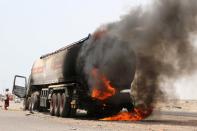 FILE PHOTO: A man stands next to an oil tanker truck set ablaze during recent clashes between Yemeni southern separatists and government forces near Aden