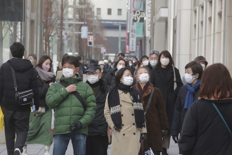 People wearing face masks to protect against the coronavirus walk on a street Wednesday, Jan. 26, 2022. (AP Photo/Koji Sasahara)