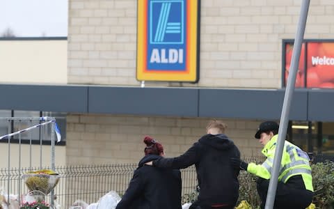 A police officer comforts mourners at the scene on Friday