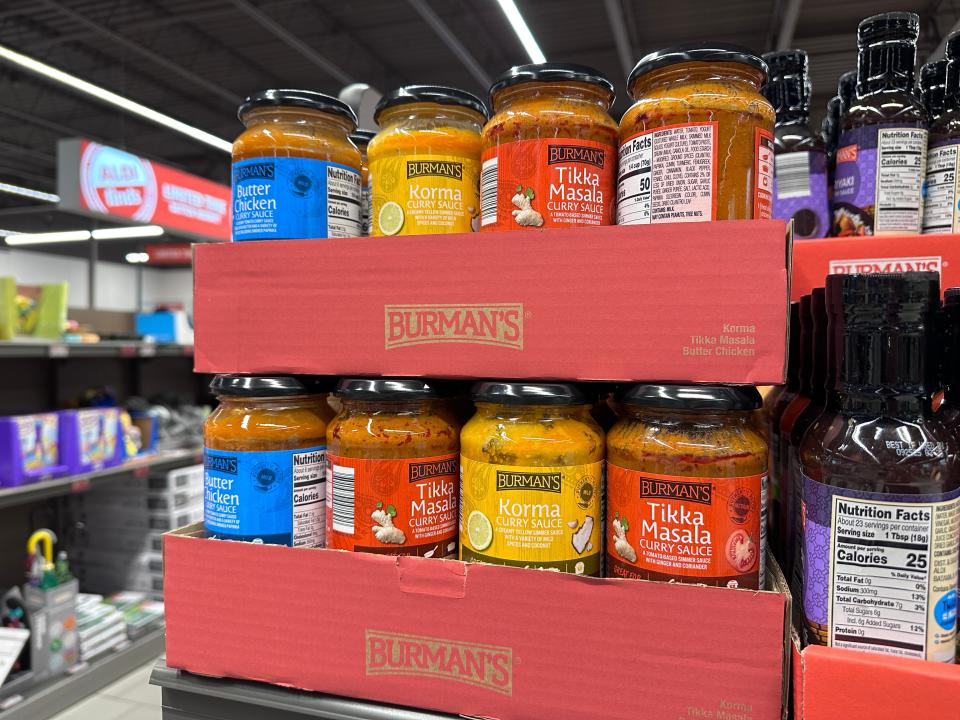 Several jars of sauces with yellow, red, and blue labels in red cardboard boxes at Aldi
