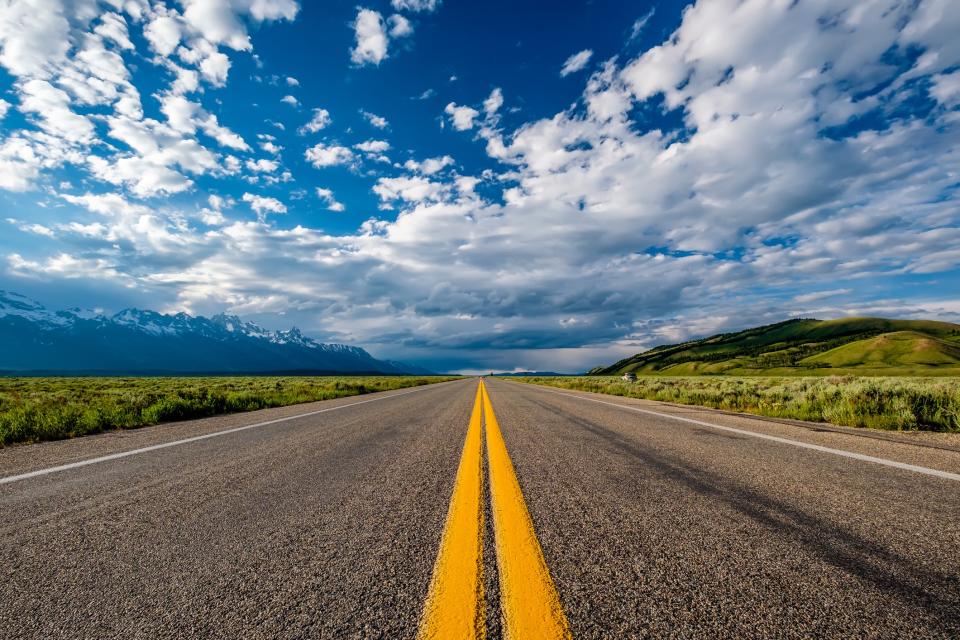 Open road with double yellow lines and blue sky.