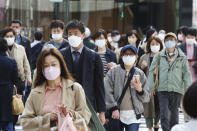 People wearing face masks to protect against the spread of the coronavirus walk on a street in Tokyo Wednesday, March 16, 2022. (AP Photo/Koji Sasahara)