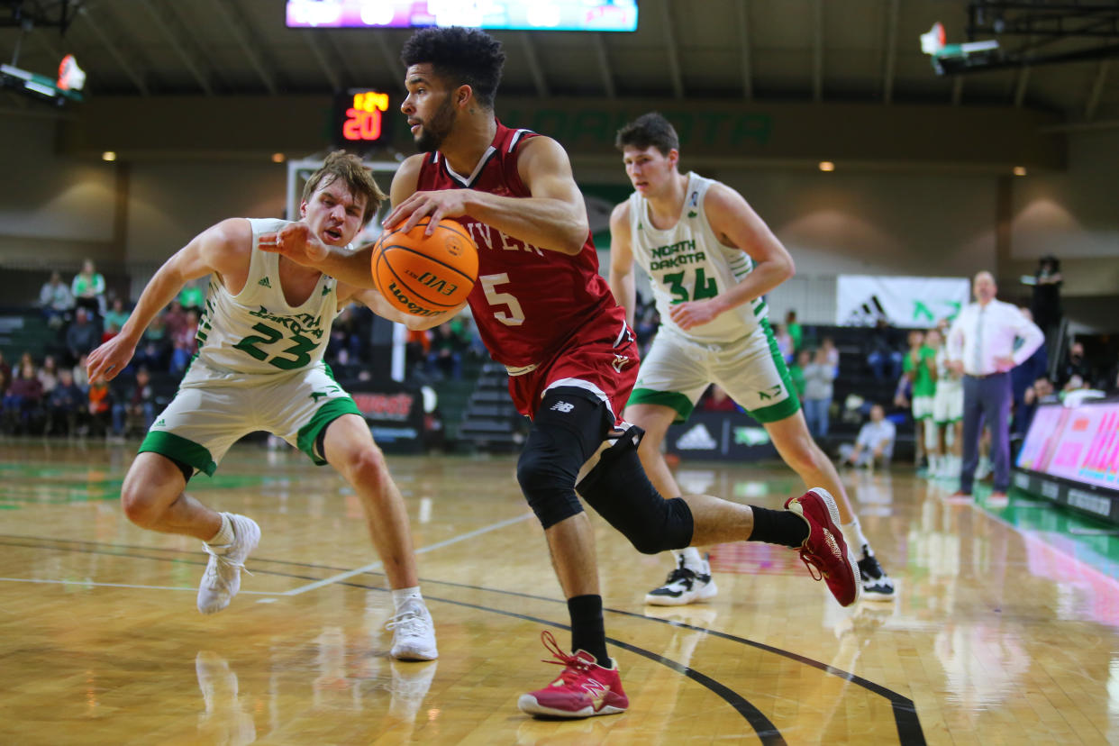 GRAND FORKS, ND - FEBRUARY 03: Denver Pioneers guard Coban Porter (5) drives to the basket guarded by North Dakota Fighting Hawks guard Paul Bruns (23) and North Dakota Fighting Hawks forward Brian Mathews (34) during the Summit League men's basketball contest between the North Dakota Fighting Hawks and the Denver Pioneers on February 3, 2022, at the Betty Engelstad Sioux Center in Grand Forks, ND.  (Photo by Jacob Kish/Icon Sportswire via Getty Images)