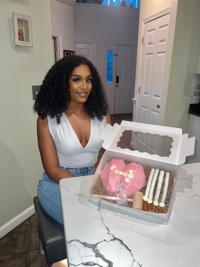 Karina Yates, owner of Sweet By Kay, a local chocolate business that specializes in chocolate covered strawberries, champagne boxes, and breakable hearts with edible custom letters. Yates is holding a breakable heart box she created for a Mother's Day client.  May 4, 2023. Holbrook.