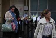 Members of King Edward VII hospital staff walk past flower tributes to late nurse Jacintha Saldanha, as they leave the residential apartments of the hospital where she was found dead, in central London, Monday, Dec. 10, 2012. Australian radio hosts managed to impersonate Queen Elizabeth II and Prince Charles and received confidential information about the Duchess of Cambridge's medical condition, in a hoax phone call to the hospital where the pregnant Duchess was staying and which was broadcast on-air. The controversial prank took a dark twist three days later with the death of nurse Saldanha, a 46-year-old mother of two, who was duped by the DJs despite their Australian accents. (AP Photo/Lefteris Pitarakis)