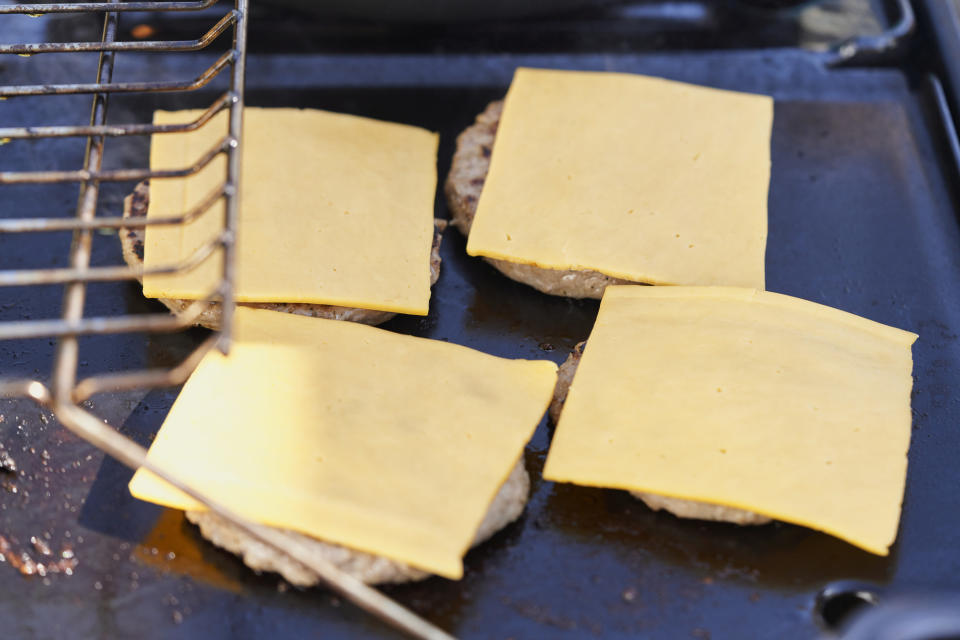 Processed American cheese on burgers over a griddle