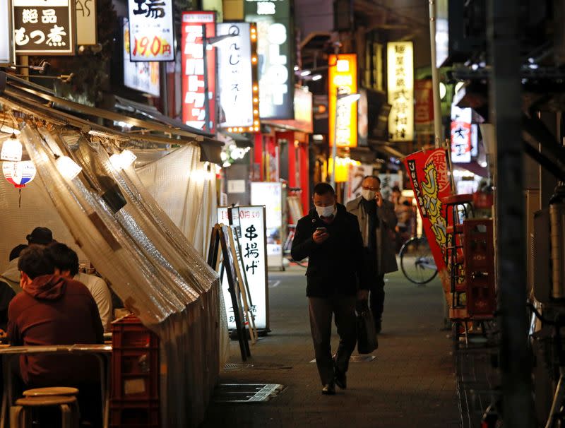 People wearing protective face masks walk past at a Japanese izakaya pub alley, amid the coronavirus disease (COVID-19) outbreak, in Tokyo