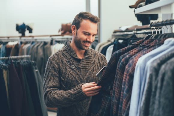 A man looking at shirts in a clothing store.