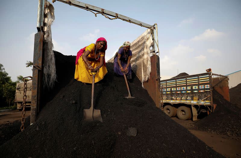 FILE PHOTO: Workers unload coal from a supply truck at a yard on the outskirts of Ahmedabad