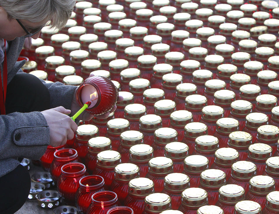 Woman lights candles during celebrations in memory of late President Lech Kaczynski, on the seventh anniversary of his death, in Warsaw , Poland, Monday, April 10, 2017. Poland on Monday is remembering the president and 95 others who died with him in a plane crash in Russia on April 10. 2010. (AP Photo/Czarek Sokolowski)