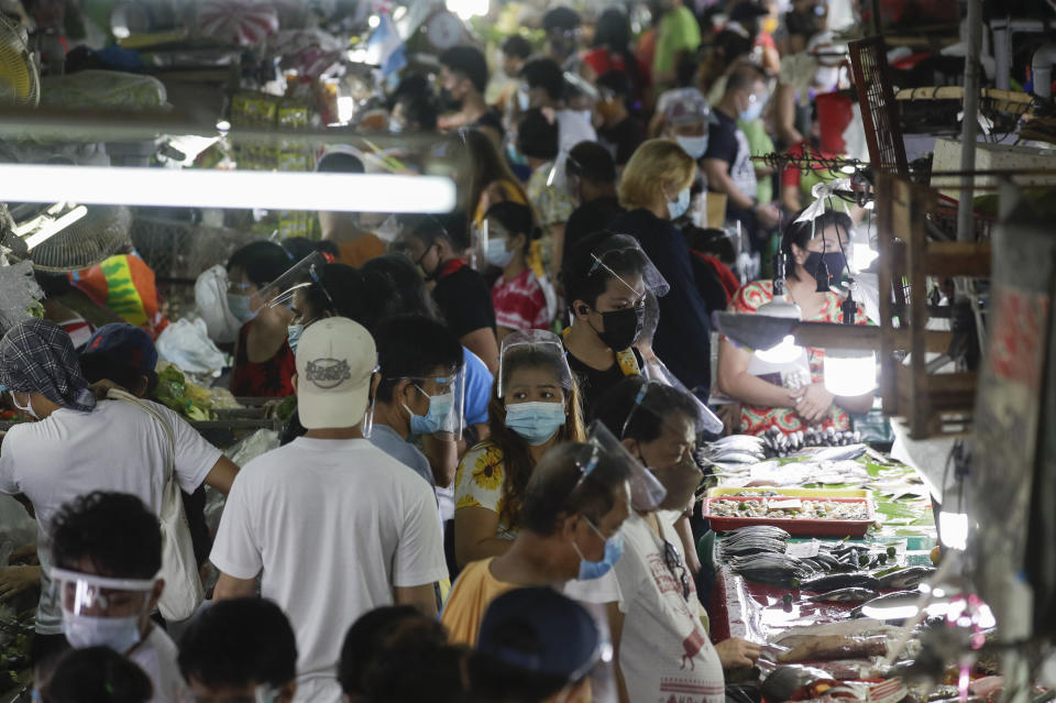 Poeple wearing face masks and face shields to prevent the spread of the coronavirus buy food at the Munoz market in Quezon city, Philippines as they prepare for a stricter lockdown on Sunday March 28, 2021. The government will start stricter lockdown measures next week as the country struggles to control an alarming surge in COVID-19 cases. (AP Photo/Aaron Favila)