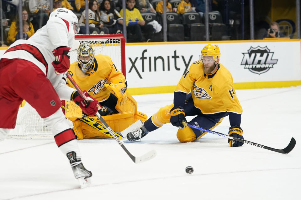 Nashville Predators defenseman Mattias Ekholm (14) slides to block the path of Carolina Hurricanes right wing Andrei Svechnikov, left, in the first period of an NHL hockey game Saturday, Oct. 16, 2021, in Nashville, Tenn. (AP Photo/Mark Humphrey)