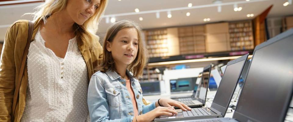 Mother and daughter looking at laptop in multimedia store