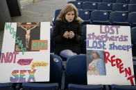 A woman sits with signs while praying the Rosary with a group during a rally outside of the Baltimore hotel where the United States Conference of Catholic Bishops are holding its Fall General Assembly meeting, Tuesday, Nov. 16, 2021, in Baltimore.(AP Photo/Julio Cortez)