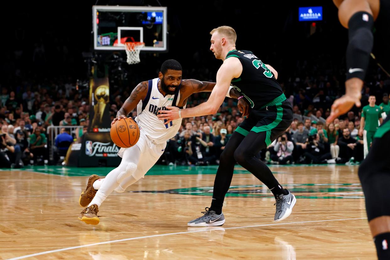 Dallas Mavericks guard Kyrie Irving (11) dribbles the ball against Boston Celtics forward Sam Hauser (30) during Game 2 at Boston's TD Garden.