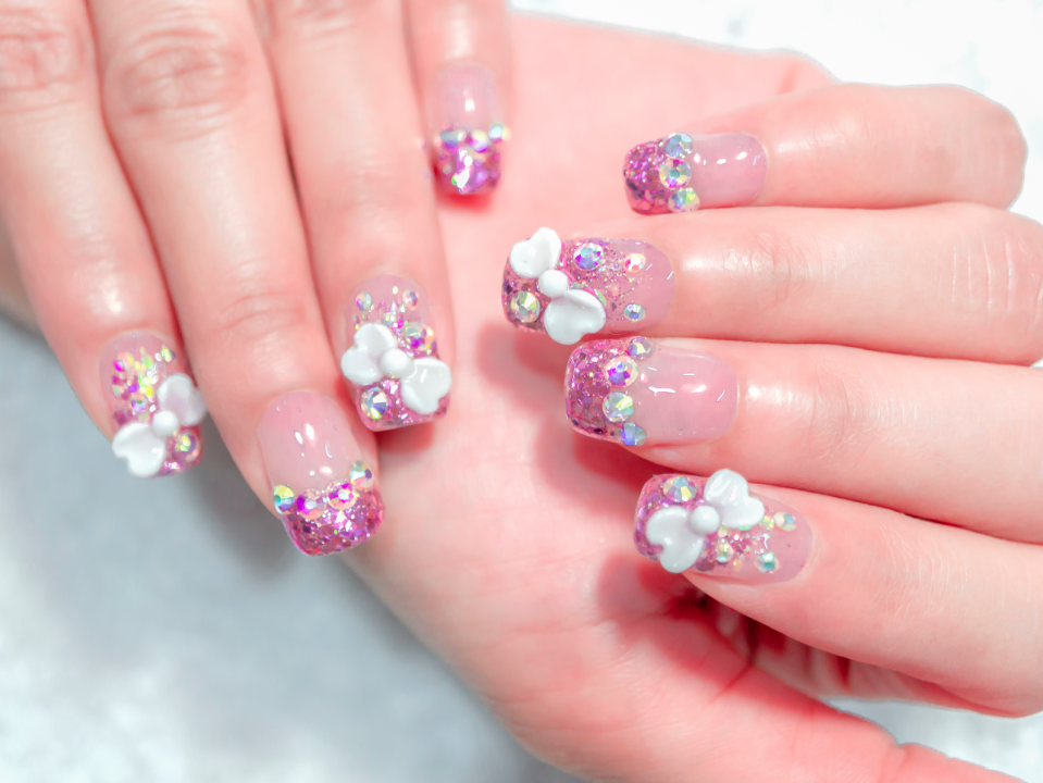 close up of a 3D manicure with sparkles, rhinestones, and bows