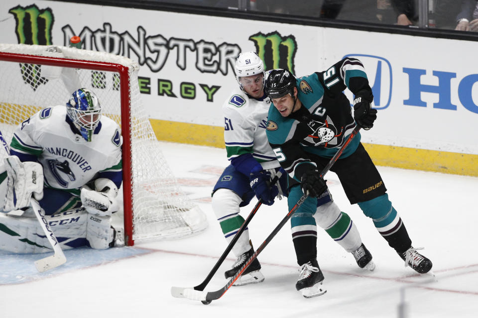 Anaheim Ducks' Ryan Getzlaf, right, is defended by Vancouver Canucks' Troy Stecher as Canucks goaltender Jacob Markstrom watches during the third period of an NHL hockey game Wednesday, Feb. 13, 2019, in Anaheim, Calif. The Ducks won 1-0. (AP Photo/Jae C. Hong)