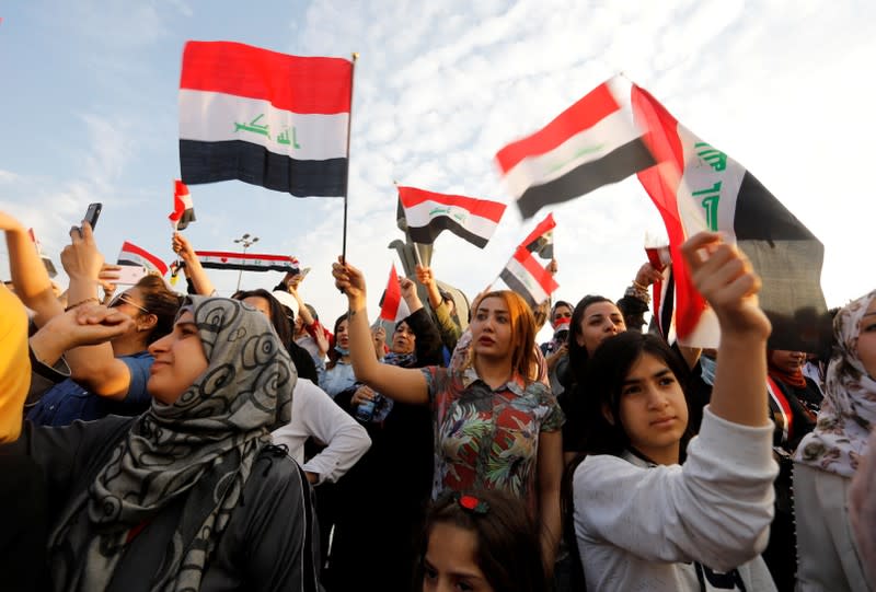 Women demonstrators hold Iraqi flags as they take part in a protest over corruption, lack of jobs, and poor services, in Baghdad