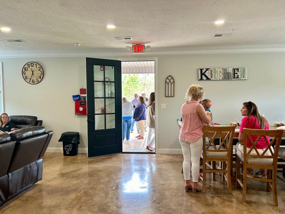 Attendees of the ribbon cutting for Aspell Recovery Center's newest sober living home talk inside of the facility on May 10, 2024 in Lexington, Tenn.