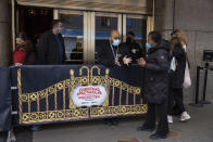 People talk with the staff member of Radio City Music Hall after cancellations of The Rockettes performance due to COVID-19 cases on Friday, Dec. 17, 2021, in New York. New York City had been mostly spared the worst of the big surge in COVID-19 cases that has taken place across the northeastern and midwestern U.S. since Thanksgiving, but the situation has been changing rapidly in recent days.(AP Photo/Yuki Iwamura)