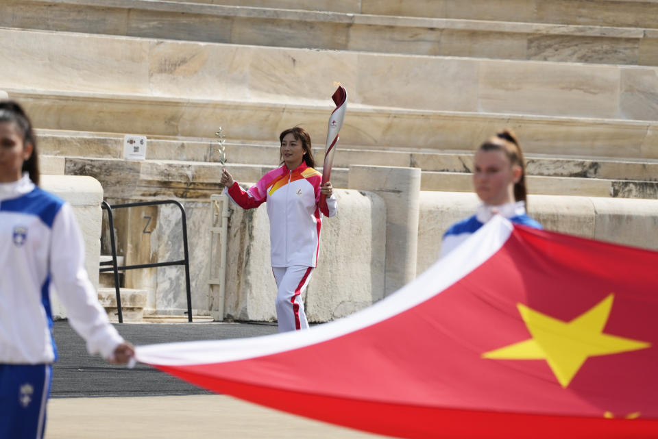 China's Olympic ski athlete Li Nina, center, runs with the torch during the Olympic flame handover ceremony at Panathinean stadium in Athens, Greece, Tuesday, Oct. 19, 2021. The flame will be transported by torch relay to Beijing, China, which will host the Feb. 4-20, 2022 Winter Olympics. (AP Photo/Thanassis Stavrakis)