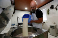 Alexey Dubovets pours milk during cheese making at his family dairy and cheese farm in the Siberian village of Sizaya, south of Krasnoyarsk, Russia August 8, 2018. Picture taken August 8, 2018. REUTERS/Ilya Naymushin