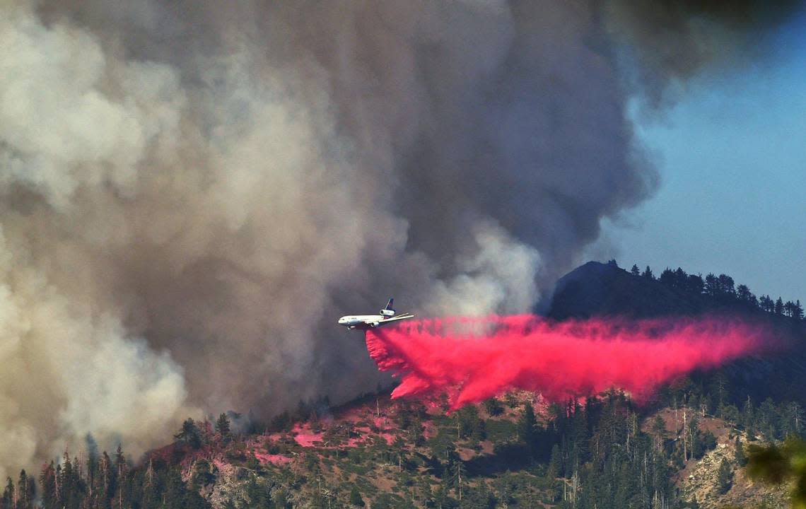 A plane drops fire retardant as the Washburn Fire as it burns near the Mariposa Grove of giant sequoias and the south entrance of Yosemite National Park Monday, July 11, 2022.