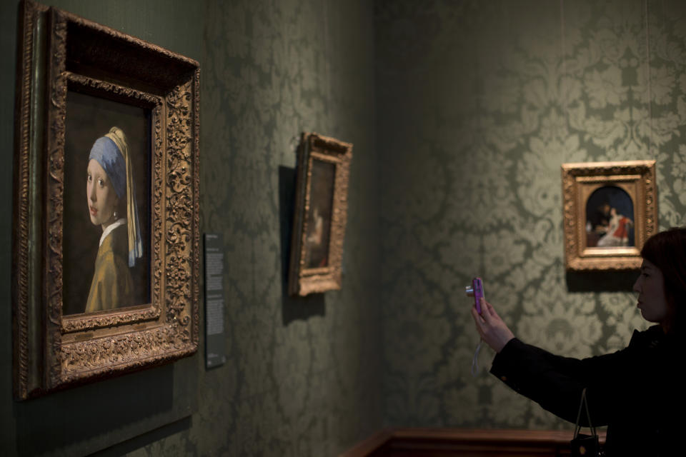 En esta foto del 20 de junio de 2014, una visitante toma una foto En esta foto de la obra maestra del siglo XVII "La joven de la perla" de Johannes Vermeer, en el museo Mauritshuis en La Haya, Holanda. (AP Foto/Peter Dejong, Archivo)