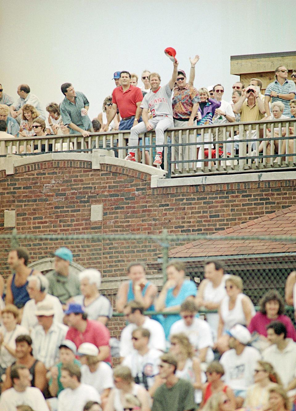 Cincinnati Reds pitcher Tom Browning, center, waves from a roof on Sheffield Avenue across from Wrigley Field in Chicago as he watches the Reds' game against the Chicago Cubs, July 7, 1993.  Browning was not scheduled to pitch.