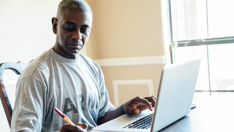 man using laptop and notebook at table