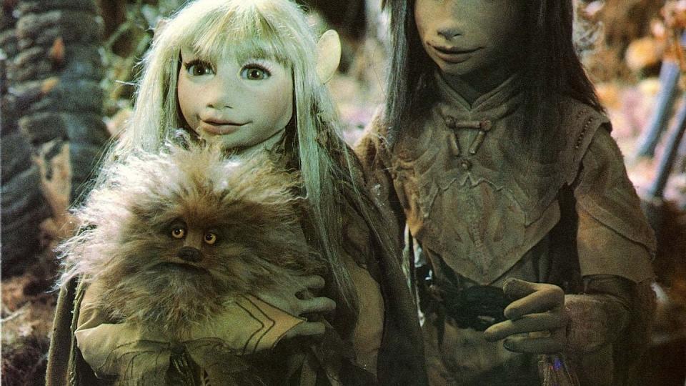 two gelflings hold an animal in a scene from the dark crystal