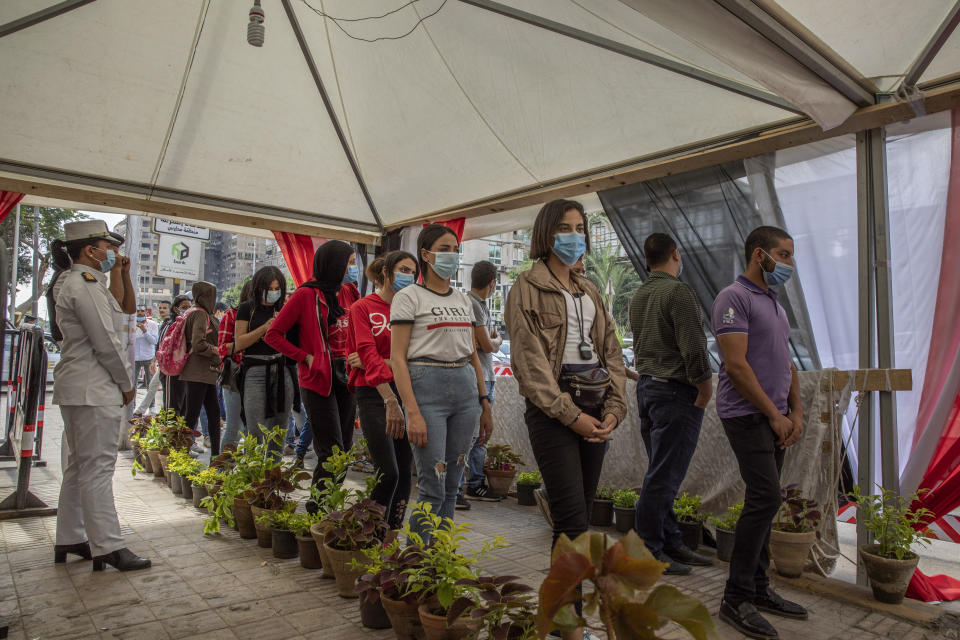 People wait in line on the first day of the parliamentary election outside a polling station in Giza, Egypt, Saturday, Oct. 24, 2020. Egyptians began voting Saturday in the first stage of a parliamentary election, a vote that is highly likely to produce a toothless House of Representatives packed with supporters of President Abdel-Fattah el-Sissi. (AP Photo/Nariman El-Mofty)